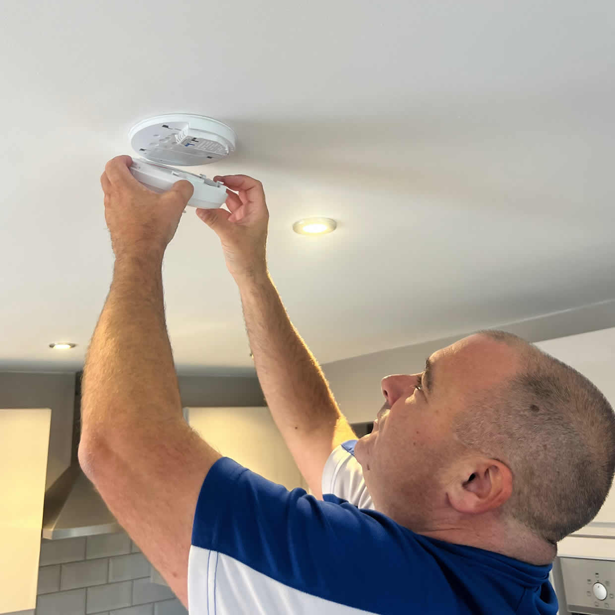 Smoke alarm installer fitting an alarm in a Guildford property